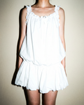 White cotton dress with ruffled straps and a pleated drop-waist skirt.