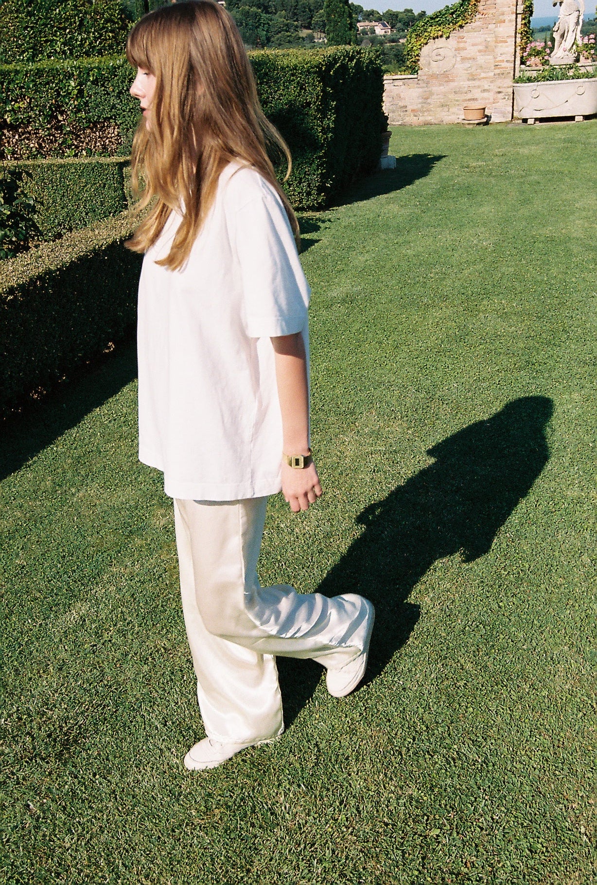 Person lying on grass wearing a white outfit with a scenic background