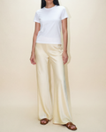 Woman wearing a white t-shirt and beige pants on a plain background